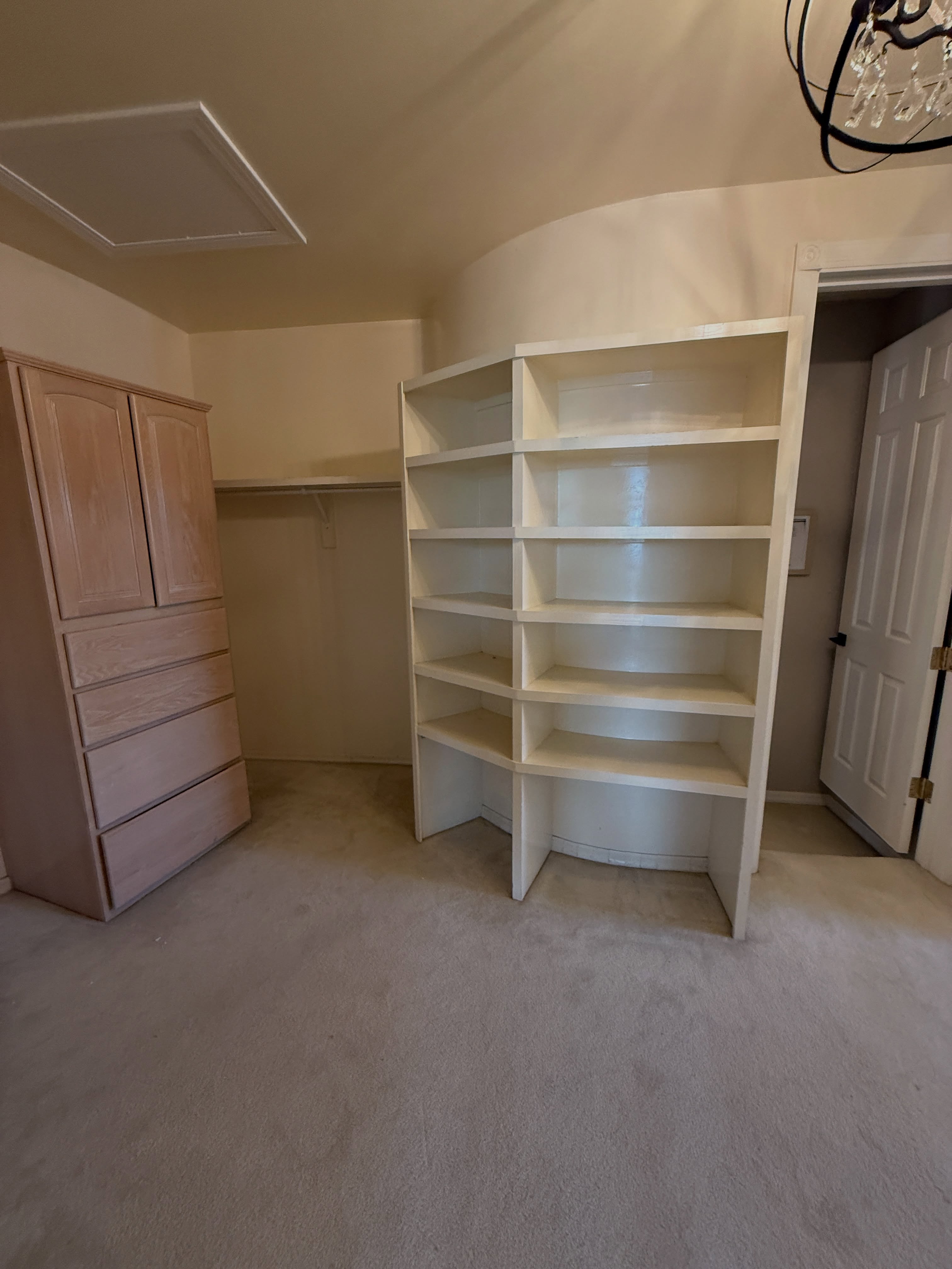 Original Paradise Valley walk-in closet with a freestanding wood cabinet, open shelving, hanging storage, and carpet before remodeling