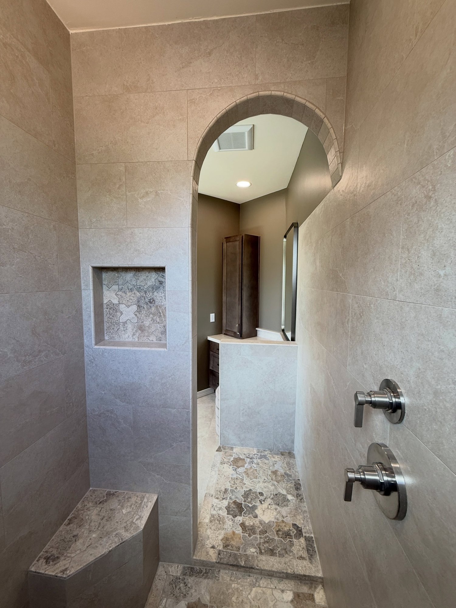 Walk-in shower: natural stone mosaic floor, bench and dual controls